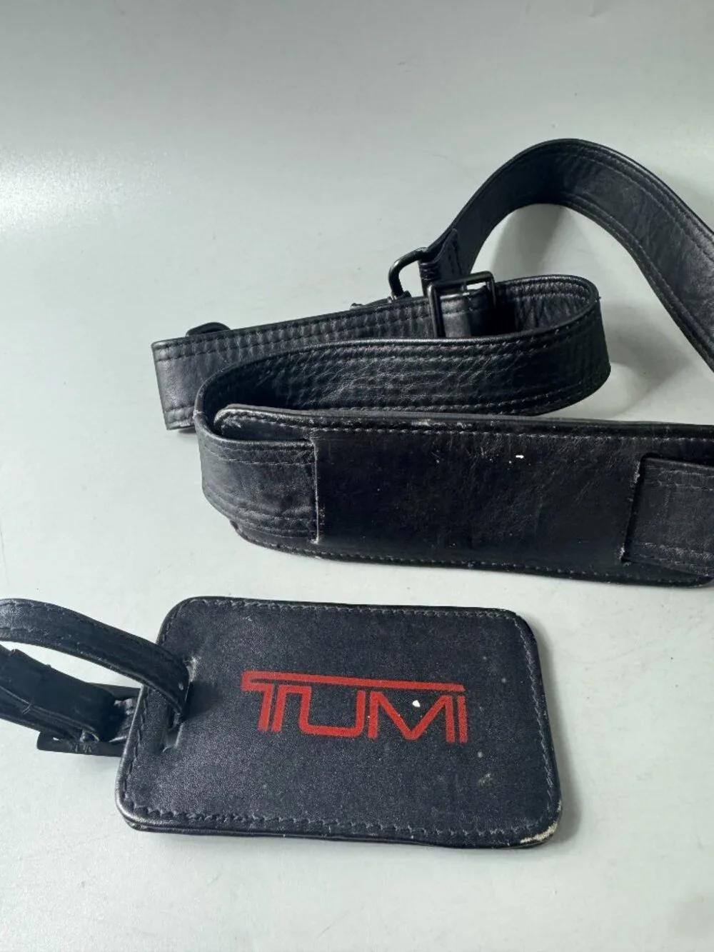A Bundle of Two (2) Vintage Tumi Black Leather Strap and Travel Tag